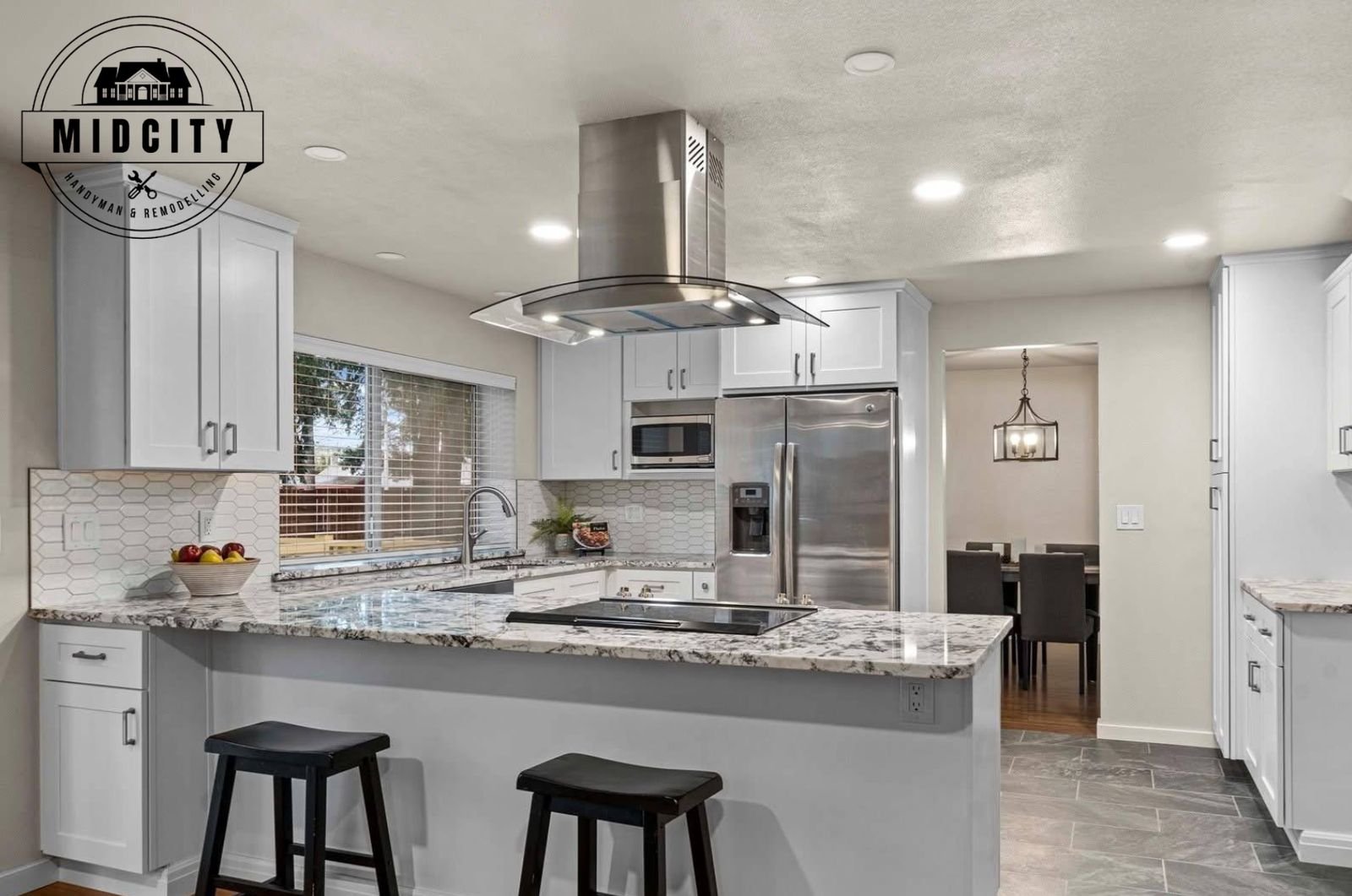 Remodeled white kitchen with center island, granite counters and stainless range hood