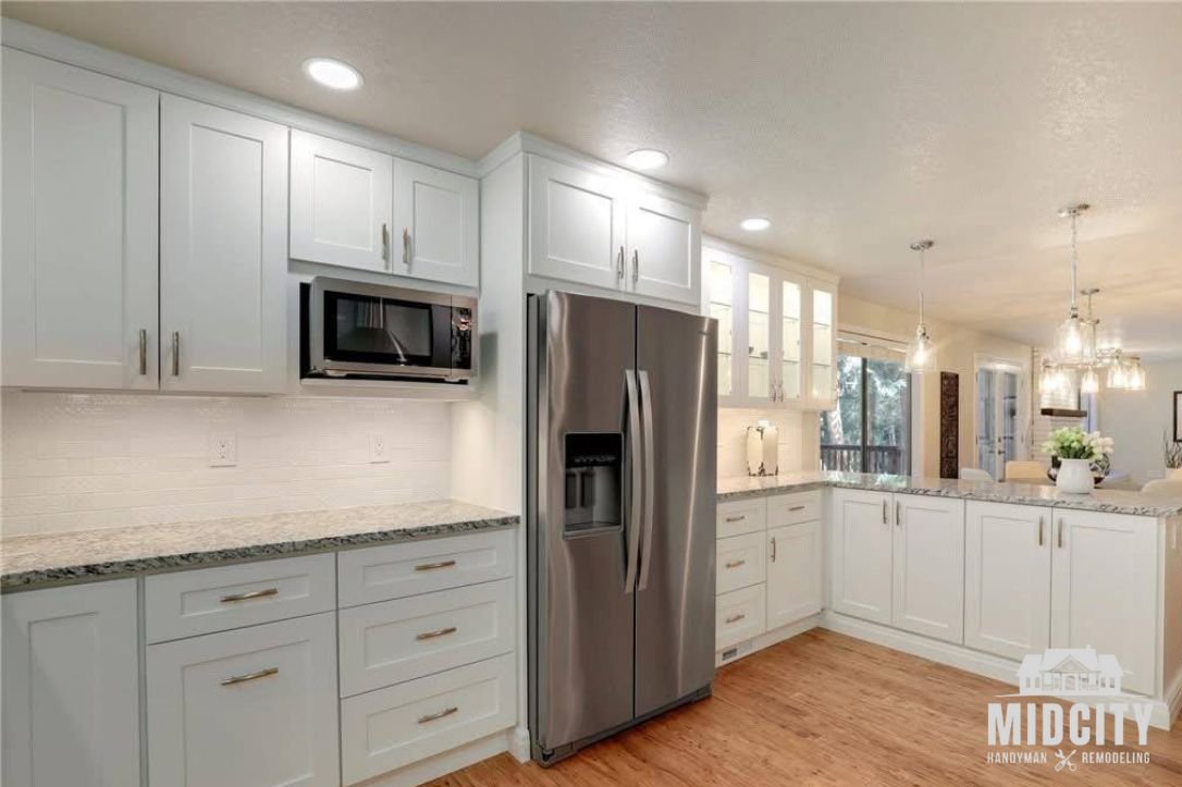 White kitchen cabinets with stainless appliances installed by Midcity Handyman & Remodeling